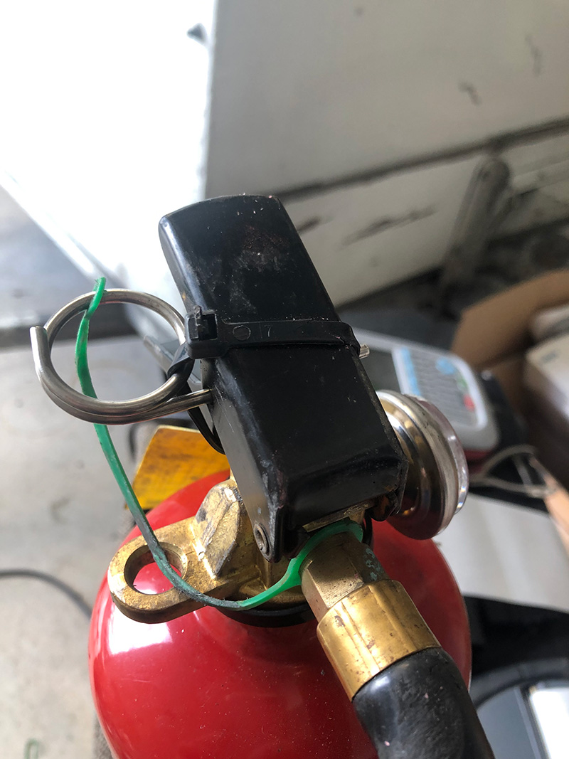 If one looks carefully one will see that holding the safety pin in place is a 4mm cable tie. Have you ever tried to break a cable tie with your dairy fingers? Not likely to happen! It was replaced with the correct anti-tamper tag these are designed to break easily when the pin is pulled.